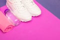 Fitness concept with white sneakers, water bottle and towel. on a pink background. Copy space