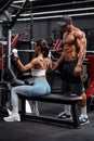 Fitness couple working out in gym doing exercise for back, man helping woman. Athletic girl doing lat pulldown Royalty Free Stock Photo