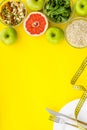 Weight loss concept with oatmeal, nuts, greenery, fruits and measuring tape on yellow background top view copy space Royalty Free Stock Photo