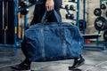 fitness enthusiast carrying denim gym bag into studio