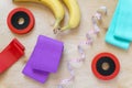 Dumbbells, rubber bands for sports, bananas and centimeter on wooden background