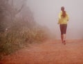 Fitness in the fog. a woman running on a trail on a misty morning.
