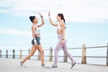 Fitness, friendship and high five, women on running path at the ocean for motivation, support and friends to workout