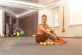 Fitness girl with blond and pink hair in black sport leggings and a red top sitting on yoga mat. Yellow dumbbells, copy space, Royalty Free Stock Photo