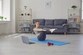 Fitness girl doing exercises on the floor and watching a training video while having a laptop in a living room. Online Royalty Free Stock Photo