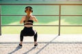 Fitness girl with earphones which doing squat exercises with fabric booty band during her sport workout on special Royalty Free Stock Photo