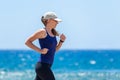 Fitness girl jogging at ocean beach on sunny day Royalty Free Stock Photo
