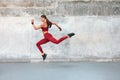 Fitness Girl Jumping. Outdoor Workout Against Concrete Wall At Stadium. Fashion Sporty Female With Strong Sexy Body.
