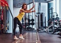 Fitness girl posing for a camera while leaning on a barbell in the modern gym Royalty Free Stock Photo