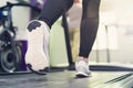 Fitness girl running on treadmill. Woman with muscular legs in modern gym, a girl in white sneakers running on a treadmill in the Royalty Free Stock Photo