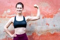 Fitness girl in sportive top shows muscules - red wall copy space