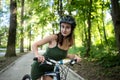 Fitness girl wear green dress rides a modern mountain bike in forest at hot summer day Royalty Free Stock Photo