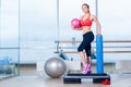 Fitness girl, wearing in sneakers, red top and black breeches, posing on step board with ball, the sport equipment Royalty Free Stock Photo