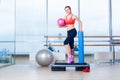 Fitness girl, wearing in sneakers, red top and black breeches, posing on step board with ball, the sport equipment Royalty Free Stock Photo