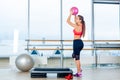 Fitness girl, wearing in sneakers, red top and black breeches, posing on step board with ball, the sport equipment Royalty Free Stock Photo