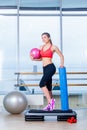 Fitness girl, wearing in sneakers, red top and black breeches, posing on step board with ball, the sport equipment Royalty Free Stock Photo