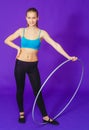 Fitness and gym concept - young sporty woman with hula hoop at gym. on a blue background Royalty Free Stock Photo