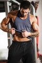 Fitness in gym, sport and healthy lifestyle concept. Handsome athletic man in blue shirt demonstrates his abs Royalty Free Stock Photo