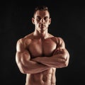 Fitness in gym, sport and healthy lifestyle concept. Handsome athletic man showing his trained body on dark background