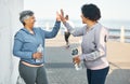 Fitness, happy and women high five by ocean for healthy lifestyle, wellness and cardio on promenade. Sports, friends and