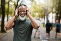 Fitness, headphone and senior black man, music and exercise in nature park, portrait and running for health and wellness