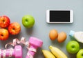 Fitness and healthy active lifestyle background concept. Dumbbell, milk bottle, apples, eggs, bananas and smart phone, tape meas