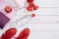 Fitness, healthy and active lifestyles Concept, dumbbells, sport shoes, bottle of waters and apple on wood background.