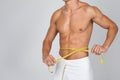 Muscular man measuring his waist with yellow tape Royalty Free Stock Photo