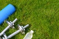 Fitness and healthy lifestyle concept, sport shoes, dumbbells, bottle of water and mat on grass