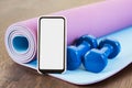 Fitness at home, smartphone app for online training, dumbbell weights and mat. Blank empty screen space, Set of workout inventory Royalty Free Stock Photo