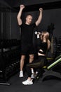 Fitness instructor conducts personal training for a girl with dumbbell in front of the mirror Royalty Free Stock Photo