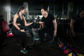 Fitness instructor exercising with his client at the gym, Personal trainer helping woman working with heavy dumbbells