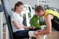 Fitness instructor wrapping bandage around female knee.