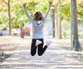 Fitness, jump and a woman outdoor for success at a park to celebrate win or achievement. Back of young female person on