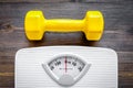 Fitness for losing weight. Bathroom scale and dumbbell on wooden background top view Royalty Free Stock Photo