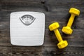 Fitness for losing weight. Bathroom scale and dumbbell on wooden background top view Royalty Free Stock Photo