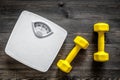 Fitness for losing weight. Bathroom scale and dumbbell on wooden background top view Royalty Free Stock Photo