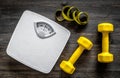 Fitness for losing weight. Bathroom scale, measuring tape and dumbbell on wooden background top view Royalty Free Stock Photo