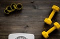 Fitness for losing weight. Bathroom scale, measuring tape and dumbbell on wooden background top view copyspace Royalty Free Stock Photo