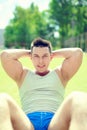 Fitness man doing abdominal exercises warming before a training outdoors, portrait sportsman on grass