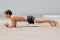 Fitness man doing push-up exercise on beach. Portrait of fit guy working out his arm muscles and body core with pushup exercises o