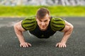 Fitness man doing push-ups in the stadium, cross training workout. Sporty male training outside