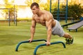 Fitness man doing push-ups in the stadium, cross training workout. Sporty male training outside