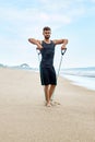 Fitness Man Exercising At Beach, Doing Expander Exercise Outdoor Royalty Free Stock Photo