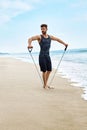 Fitness Man Exercising At Beach, Doing Expander Exercise Outdoor Royalty Free Stock Photo