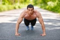 Fitness man exercising push ups, outdoor. Muscular male cross-training on city park