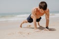 Fitness man exercising push ups smiling happy. Male fitness model cross-training on beach. Royalty Free Stock Photo