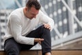 fitness man have knee pain sitting on steps of stair in the city. sport injury leg of run in urban , accident , exercise,workout Royalty Free Stock Photo