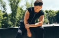 Fitness man resting after running and exercising, listening the music on earphones outdoors. Young muscular male rest after a hard Royalty Free Stock Photo