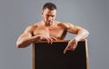 Fitness man with sign ad board. Strong bodybuilder macho holding blank poster isolated on gray background. Royalty Free Stock Photo